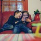 Two kids look at a smartphone at home