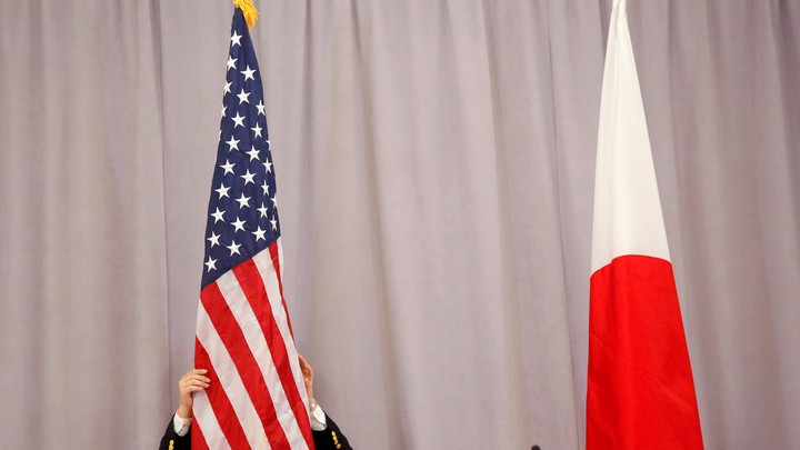 A worker adjusts the U.S. flag before Japanese Prime Minister Shinzo Abe addresses media following a meeting with President-elect Donald Trump in New York City on November 17, 2016.