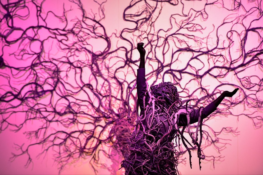 A sculpture that looks like a human figure partly made from, and tangled up in, branching roots
