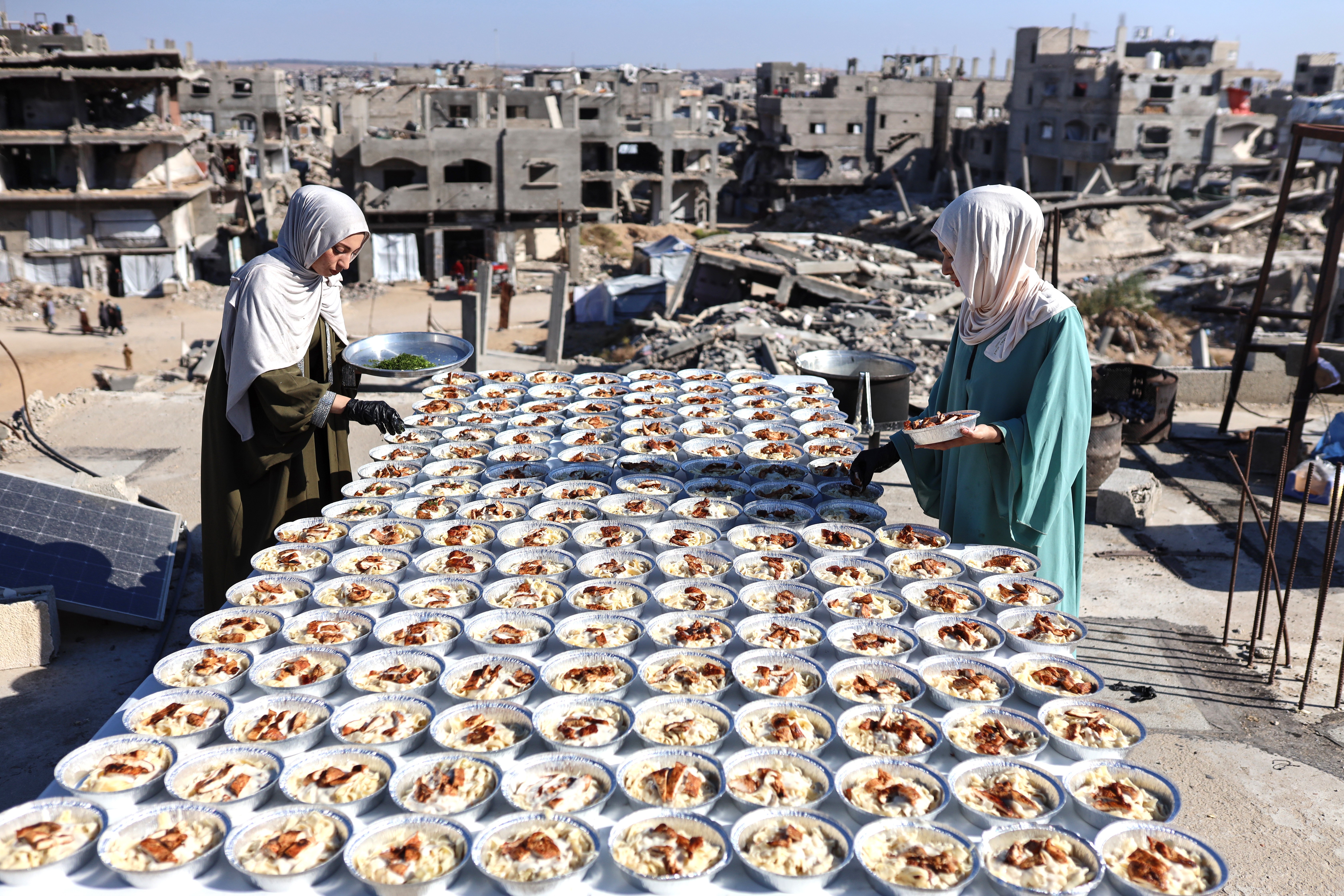 Two sisters prepare dozens of food plates on the rooftop of their house in Gaza.
