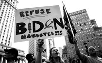 A woman holds a sign reading "Refuse Biden mandates!!!"