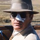 A movie still of Jack Nicholson, playing private eye J. J. Gittes in Chinatown (1974), in a convertible car with the top down, wearing a fedora and sunglasses with his nose covered in white medical tape.