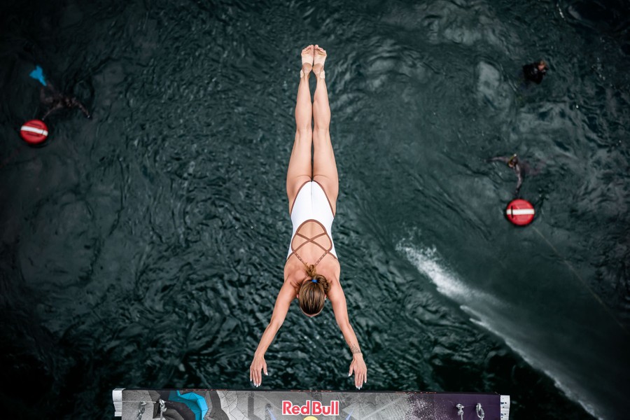 A view, looking down, of a diver jumping off a high bridge.