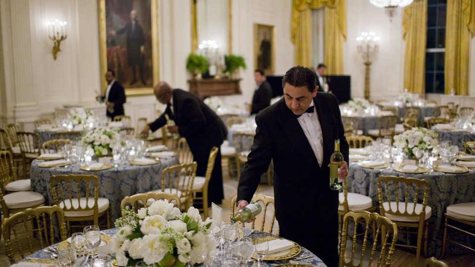 A butler pours wine before a congressional dinner at the White House.