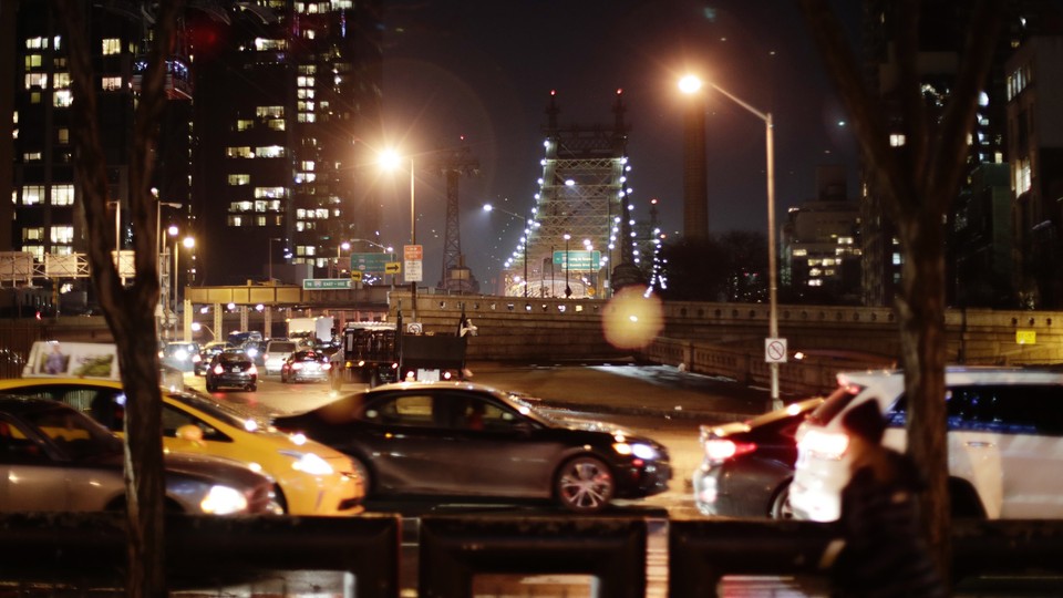 Cars driving at night in front of the Queensboro Bridge