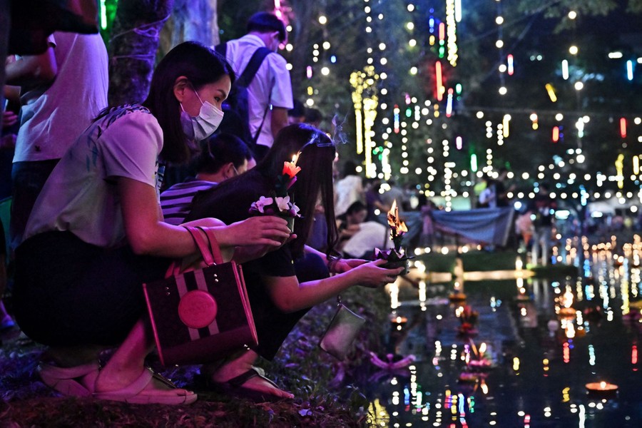 People release floating lanterns in a pond at night.