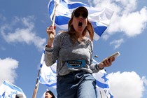 Low angle shot picture of woman holding Israeli flag and screaming.