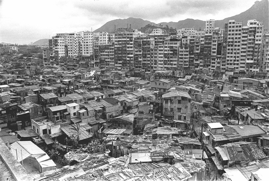A black-and-white photograph of a densely populated neighborhood in Hong Kong, including many tall buildings clustered together