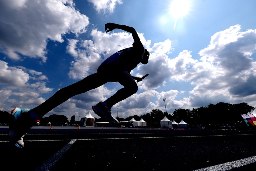 An athlete takes off, starting a race, seen in silhouette.