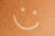 Tanned skin with pale smiley face drawn on it