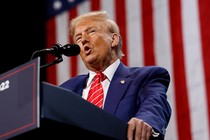 Photo of Donald Trump giving a speech at a podium with an American flag hanging behind him