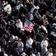 In a crowd of Catholics, one holds up an American flag.