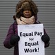 A woman holds a sign saying "Equal pay for equal work"