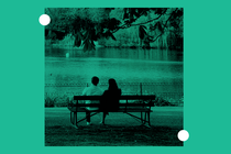 A couple sits on a bench in the park