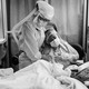 Romelia Navarro is comforted by Michele Younkin, a nurse, while sitting at the bedside of her dying husband.