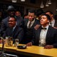 Men dressed in 1960s attire sitting at a bar