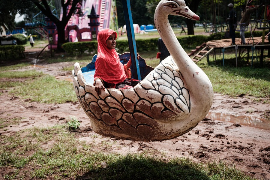 A girl rides a swan-shaped amusement ride.