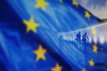 People walk behind a waving flag of the European Union