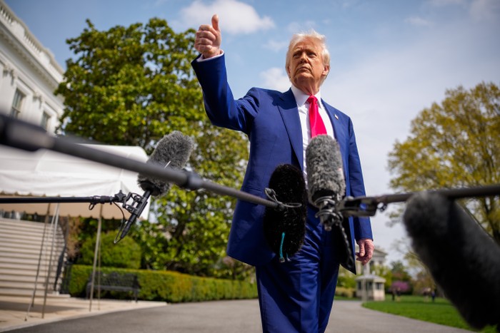 Donald Trump holds a thumbs up in front of boom mics