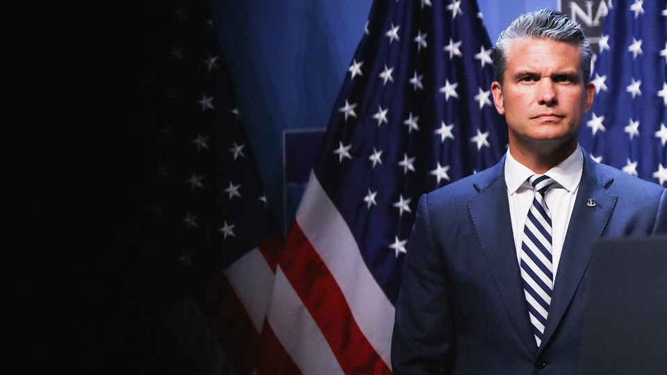 Pete Hegseth standing in front of American flags