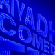 An illuminated neon blue sign reads "Riyadh Comedy Festival"