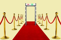 A red carpet leading up to a TSA body scanner