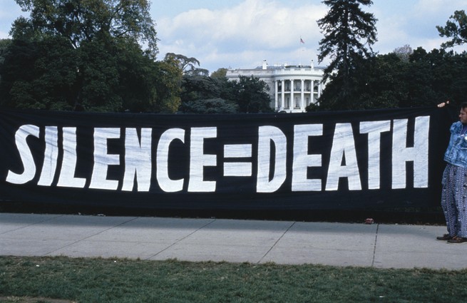 An AIDS protest in front of the White House. ACT UP activists hang a "Silence = Death" banner on the White House gates.