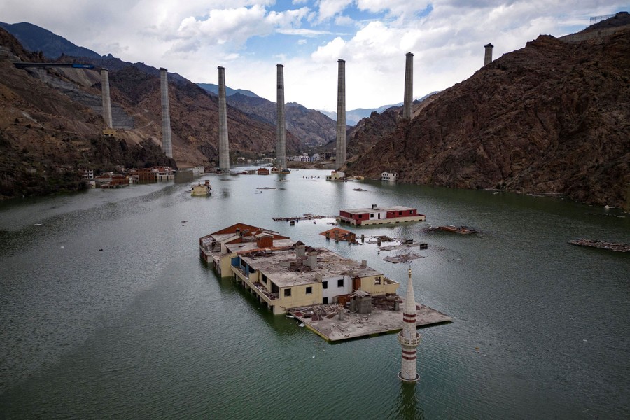 Buildings and the top of a minaret sit in the rising waters of a reservoir.