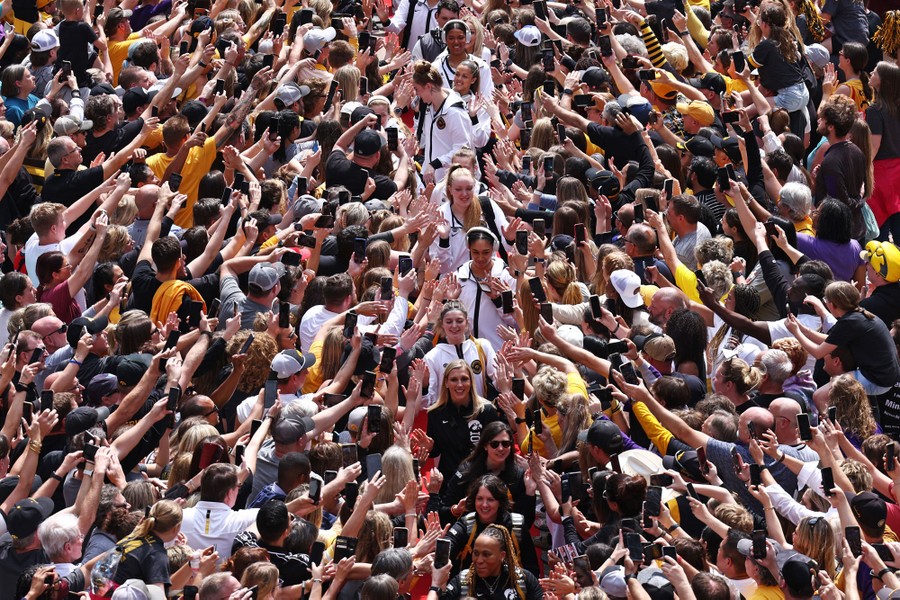 Basketball players walk in a line amid a throng of excited fans.