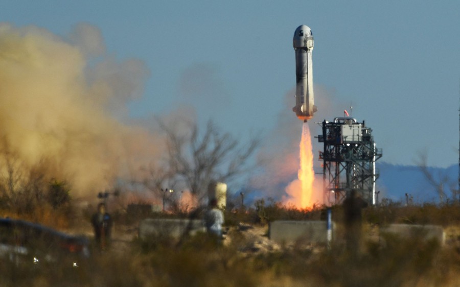 A rocket lifts off in an arid landscape.