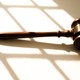 judge's wooden gavel sitting on a table against a sunny white background/shadow detail