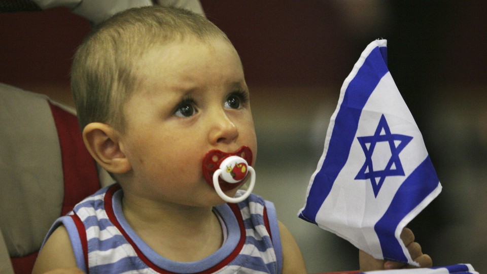 A baby holds an Israeli flag.