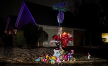 Balloons, flowers, and stuffed animals adorn a stop sign at the corner of Castlegate Lane and Bear Creek Cove.