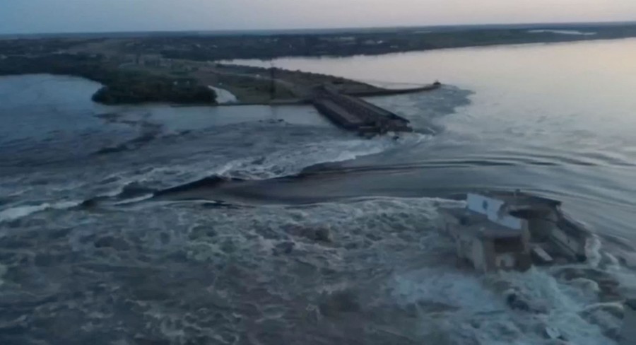 An aerial view of a large amount of water rushing through a destroyed dam