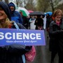 A woman at a rally holds a sign that says "Science: Make America Great Again!"