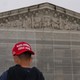Photograph of a boy wearing a backwards “Make America Great Again” cap in front of the Supreme Court building with scaffolding