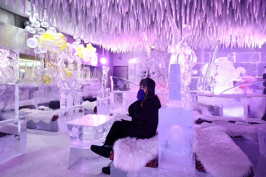A person sits in a well-lit room filled with various ice sculptures.
