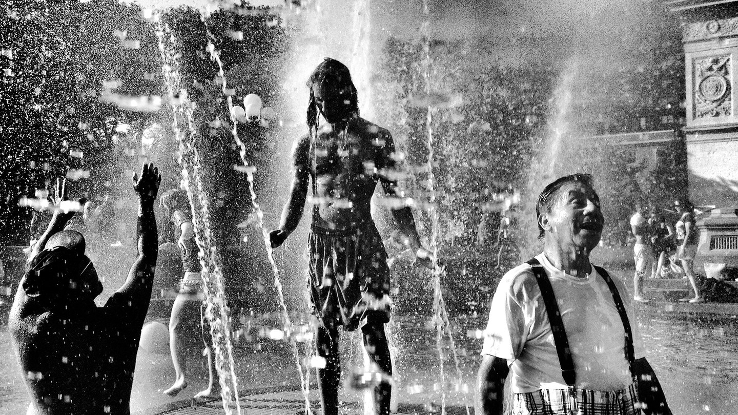 A black-and-white photo of people in a fountain, by Clay Benskin