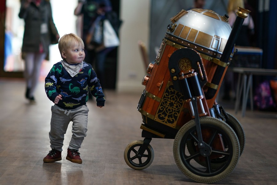 A young child looks at a steampunk version of the Star Wars character R2-D2.