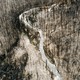 A river in Colorado flows through hillsides burned in the Cameron Peak Fire. The trees are stark and black, burnt, and the soil around them is beige and gray.