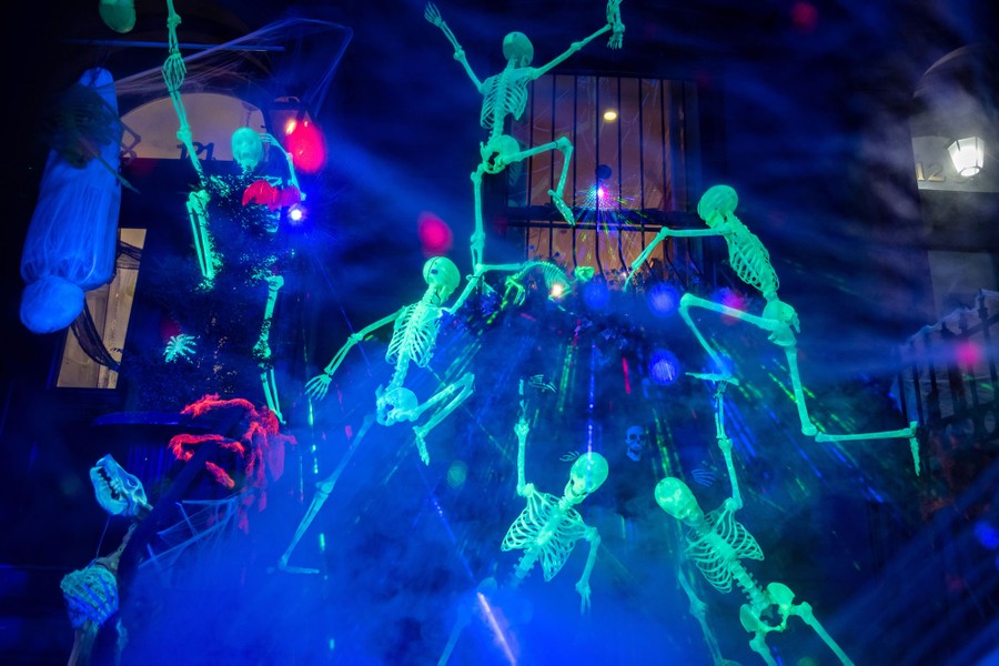 A half-dozen glowing skeletons appear to be climbing other decorations outside a home.