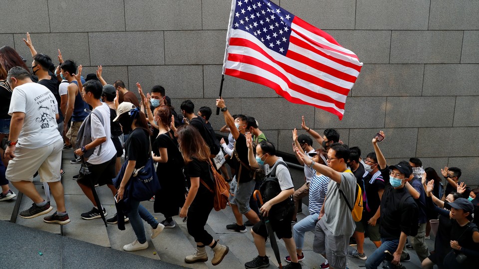 Hong Kong protesters hold up five fingers and brandish an American flag during a march.