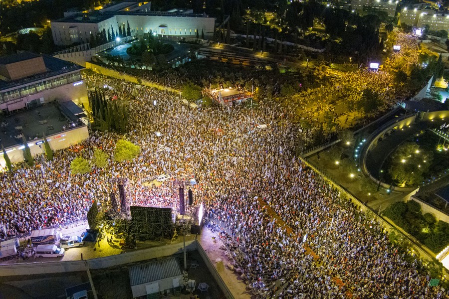 An aerial view of a large group of protesters standing at a wide intersection