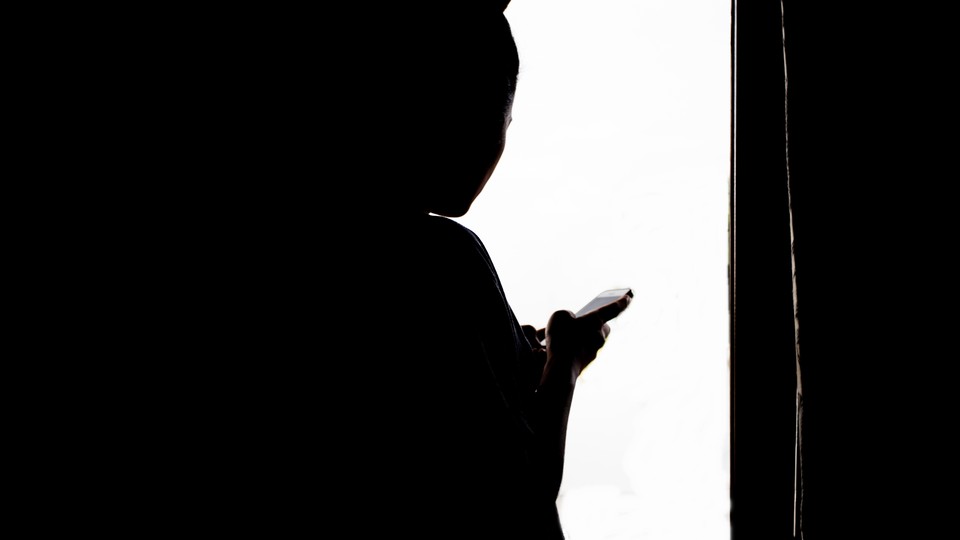A silhouette of a person checking their phone