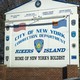 A sign reading "City of New York Correction Department: Rikers Island, Home of New York's Boldest"