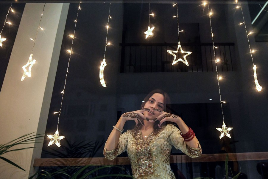 A woman poses for a photograph, forming a heart with her fingers.