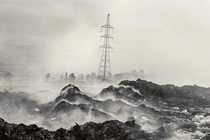 A high-voltage electricity pylon behind a plume of smoke from burning garbage, mostly plastic and textiles, at the Gioto dumpsite