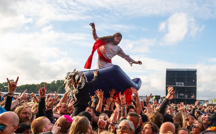 A fan dressed as Jesus crowd surfs during a concert.