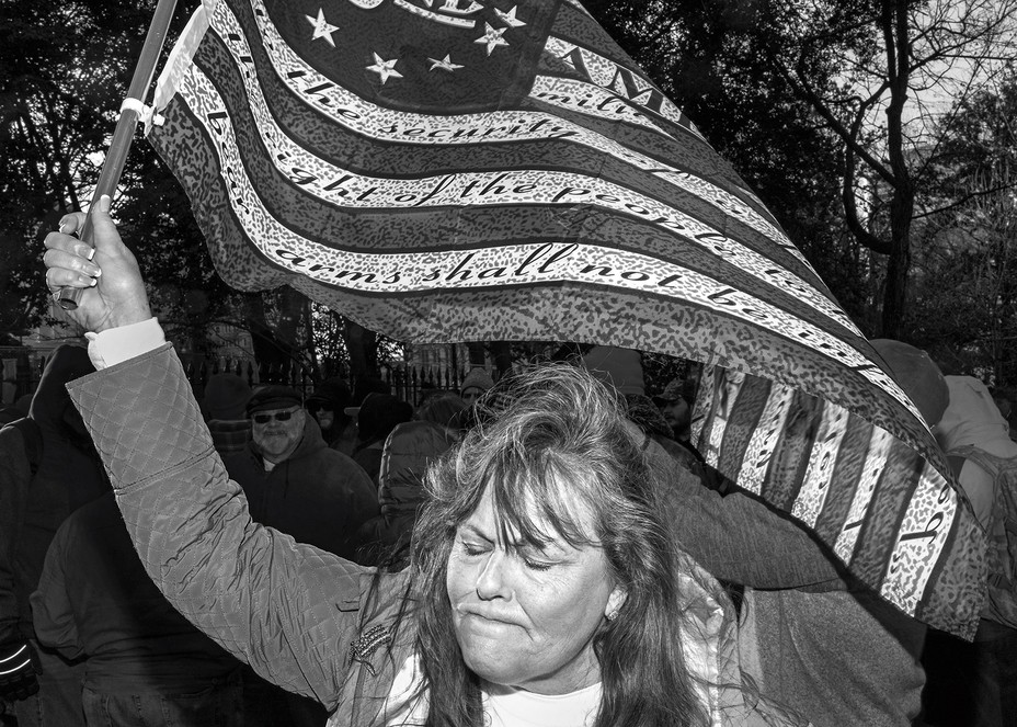 photo of woman grimacing with eyes closed waving American flag with 2nd Amendment text printed in the white strips
