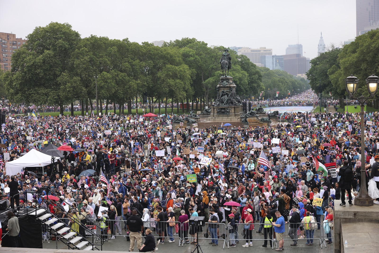 A large crowd of protesters fills a long city square.